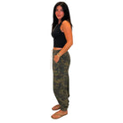 A woman modeling a pair of olive green camouflage cargo pants with a white drawstring, paired with a black crop top and sandals, set against a plain white background.