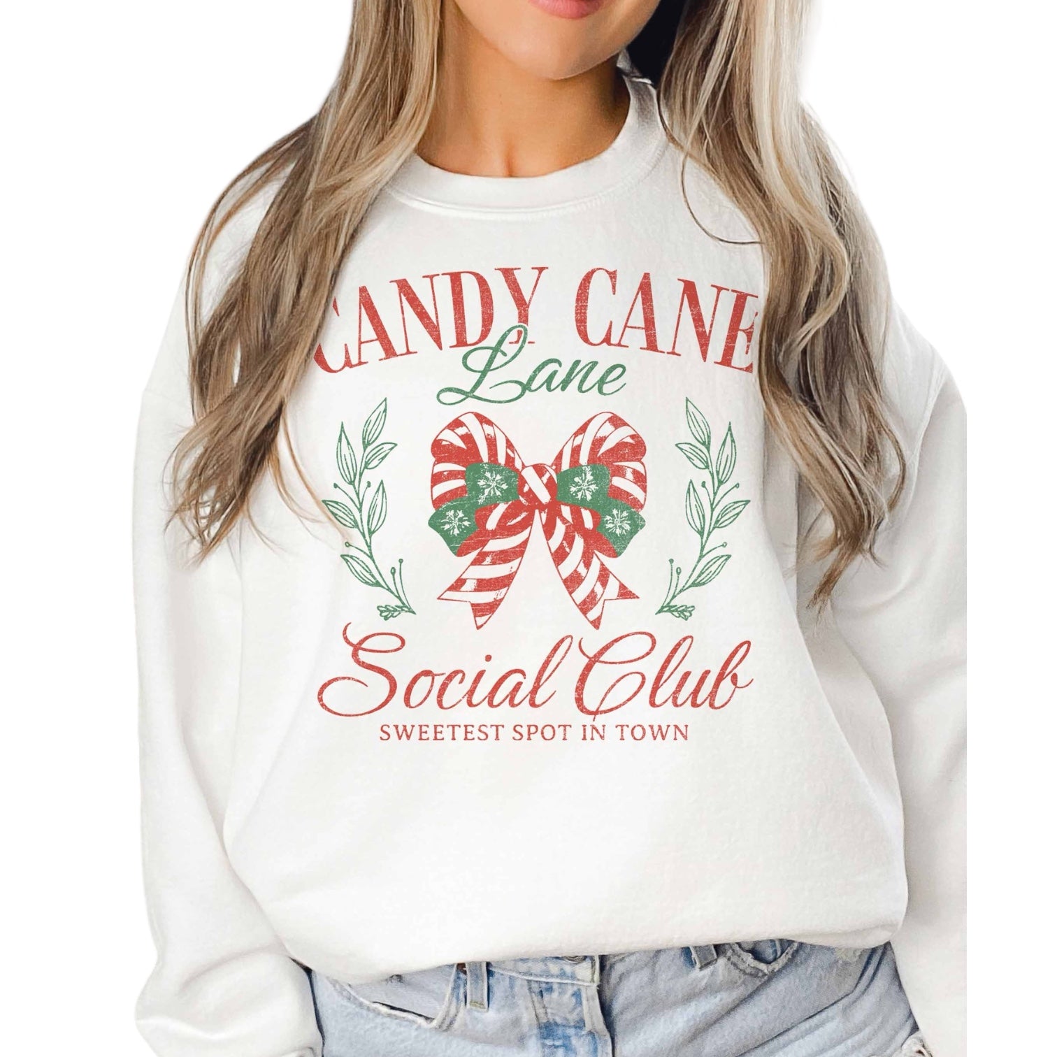 White sweatshirt with Christmas-themed design featuring a candy cane and bow, worn by model.