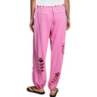 Pink distressed sweatpants worn by a person on a white background