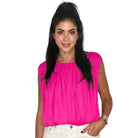 Woman wearing a bright pink sleeveless top on a white background