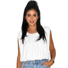 Woman wearing a white sleeveless top and blue jeans on a white background