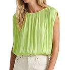 Woman wearing a light green sleeveless top on a white background