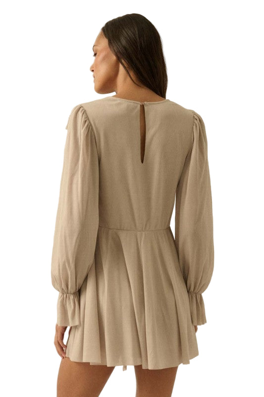 Woman wearing a beige romper with long sleeves on a white background