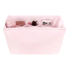 Pink organizer bag with compartments containing various items on a white background