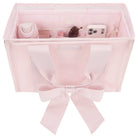 Pink fabric organizer with a bow, holding various items on a white background
