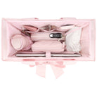 Pink makeup bag with various cosmetic items on a white background