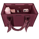 A burgundy tote organizer bag shown from above, filled with travel accessories including a pink tumbler, a phone case, a small box, and a scarf tied to the handles. The brand name 'BAGS & LOVE' is visible on the front and inside the organizer.