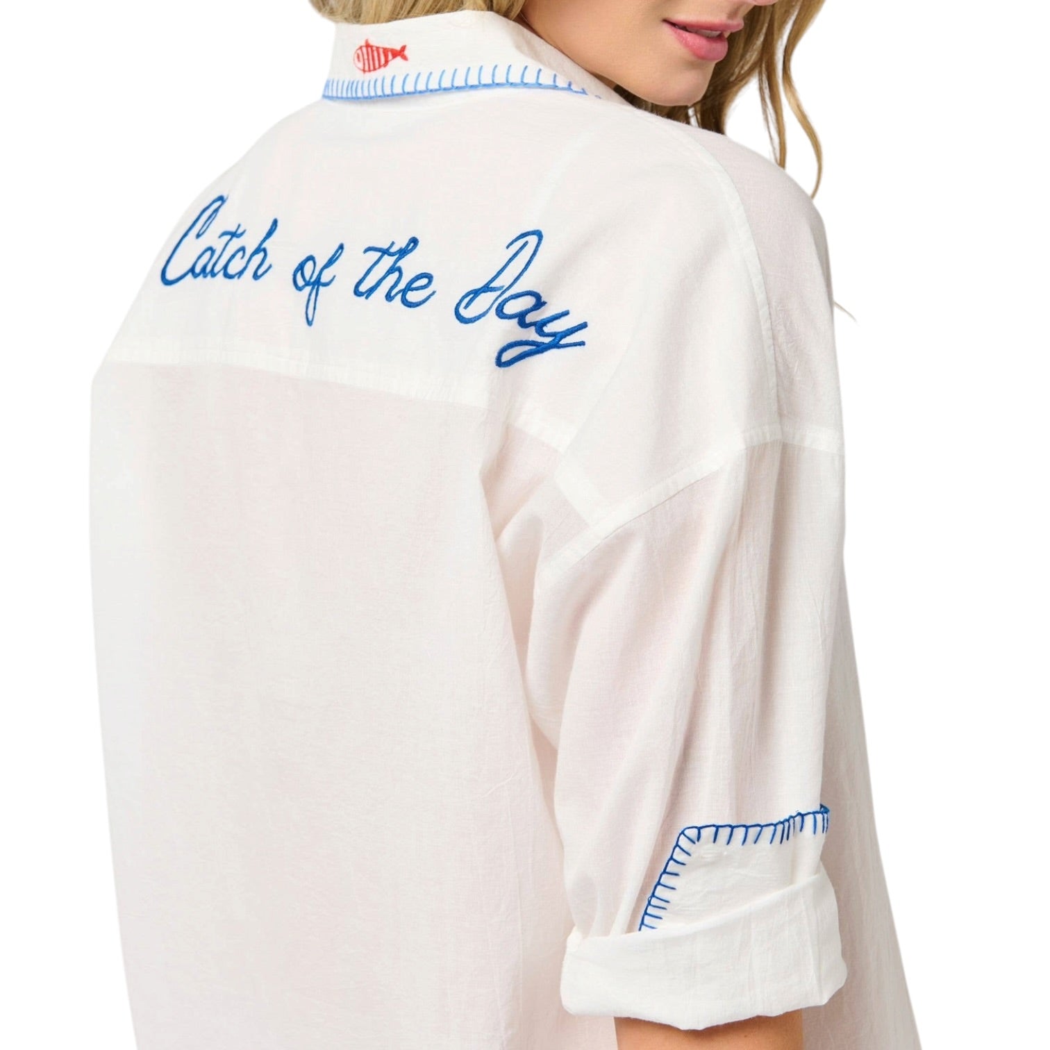 woman wearing white button down cover up that says "Catch of the Day" on the back
