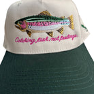 Green cap with embroidered fish and text on a beige background