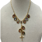 A gold-tone necklace displayed on a cream fabric mannequin bust. The necklace features a chain with multiple oval religious medallions depicting the Holy Family (Jesus, Mary, and Joseph) and a dangling cross at the bottom.