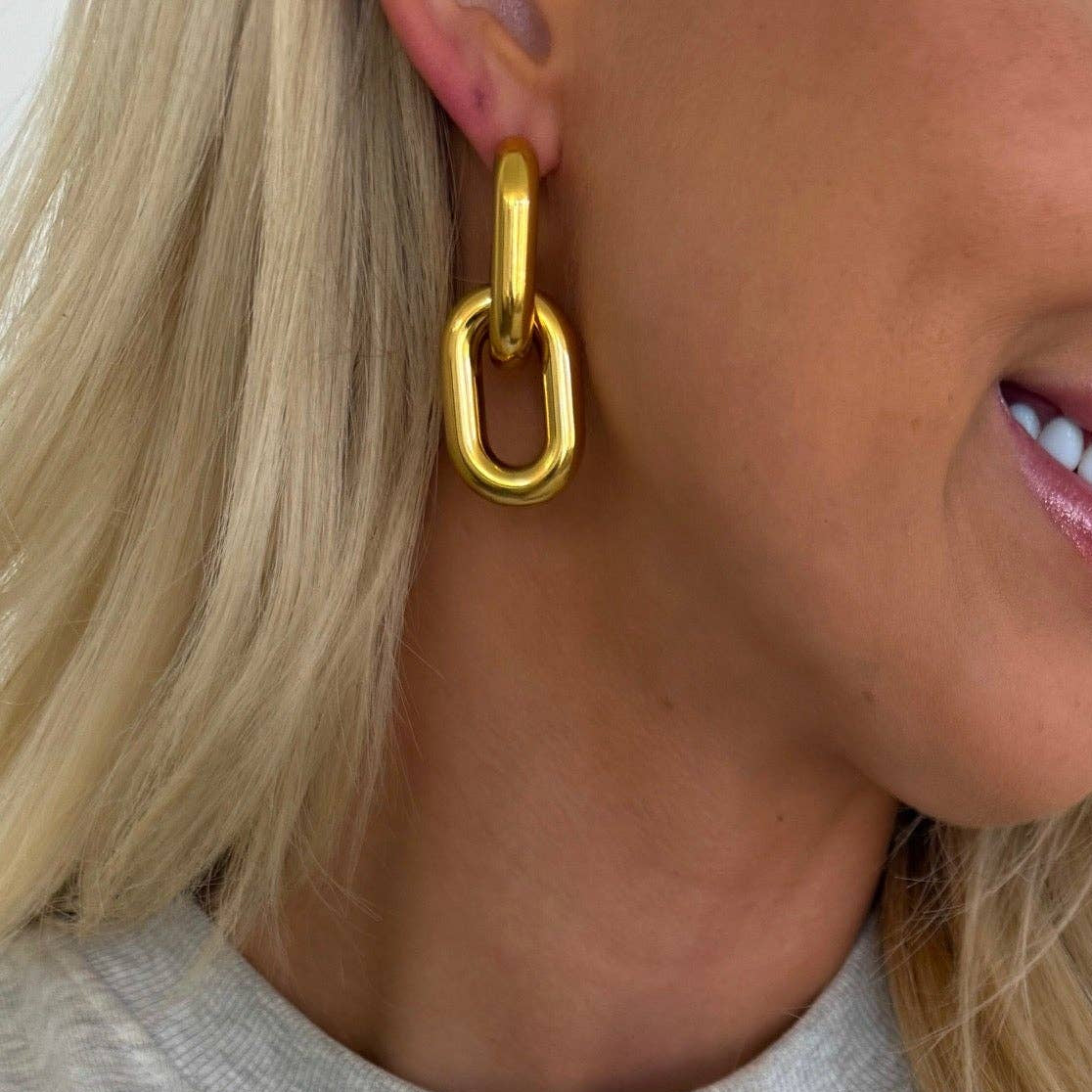 Gold chain earring worn by a person with blonde hair.