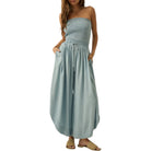 Woman wearing a strapless, light blue jumpsuit on a white background