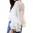 White blouse with ruffled sleeves worn by a person on a white background