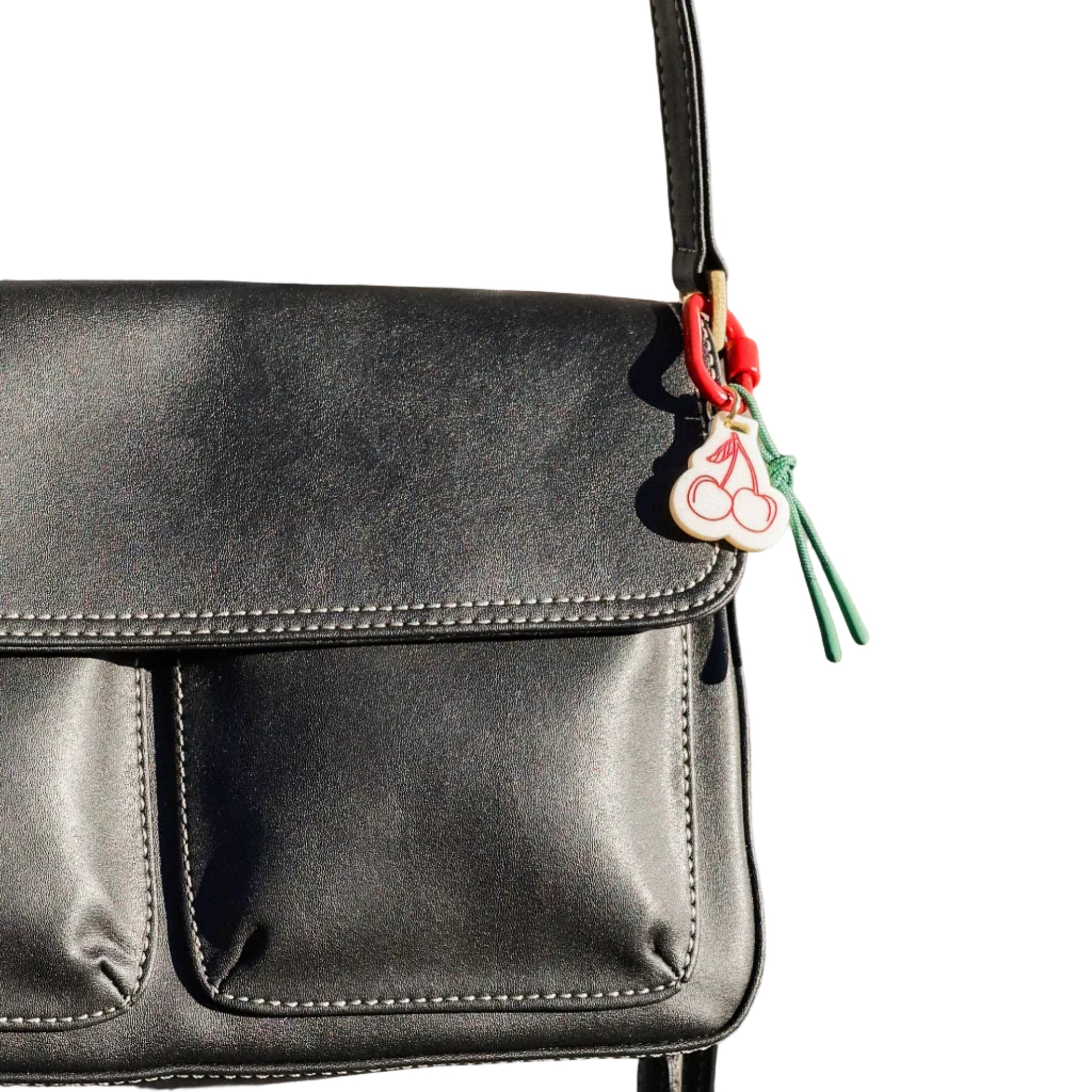 Black leather handbag with a decorative tag on a textured surface