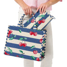 Tote bag with blue stripes and cherry design held by a person