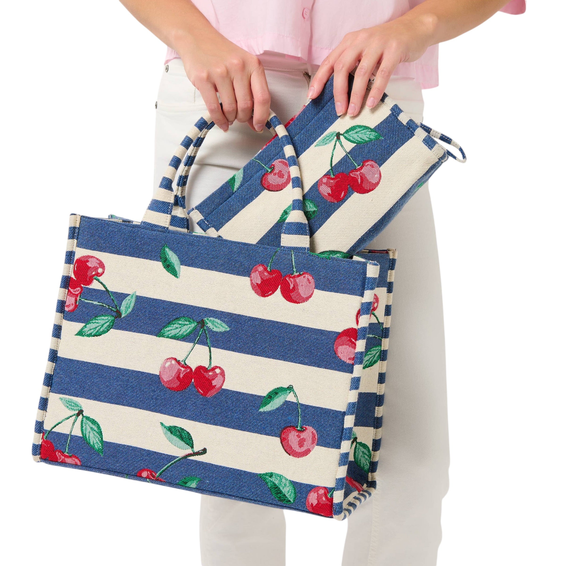 Tote bag with blue stripes and cherry design held by a person