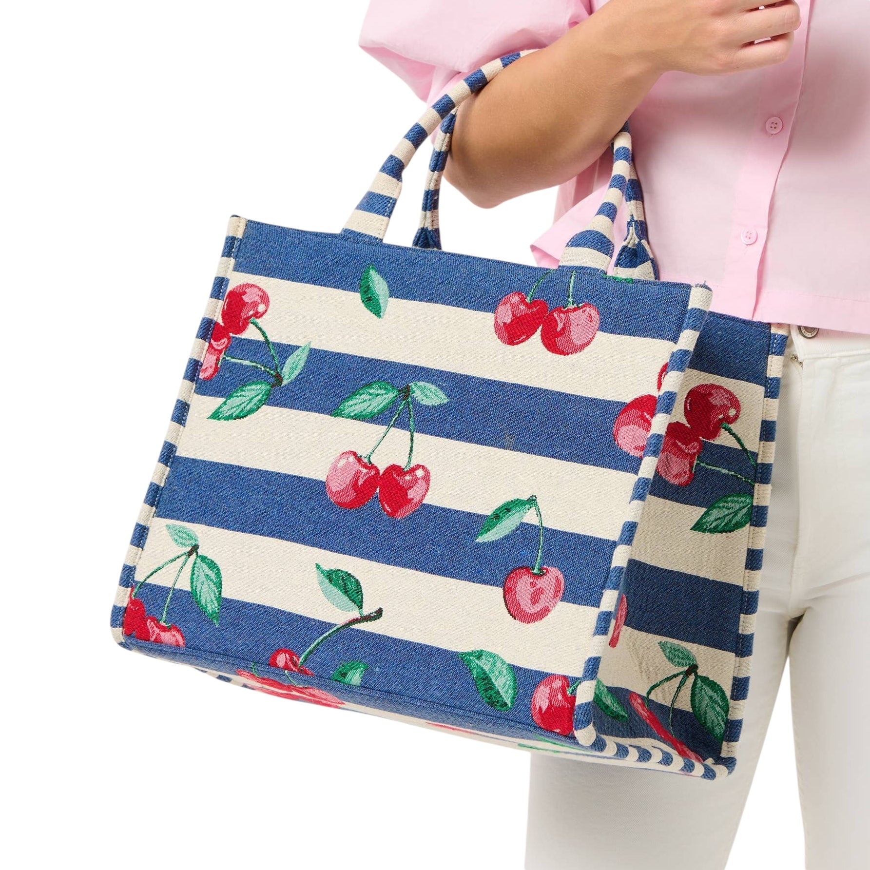 Tote bag with blue and white stripes and cherry design held by a person wearing a pink shirt.