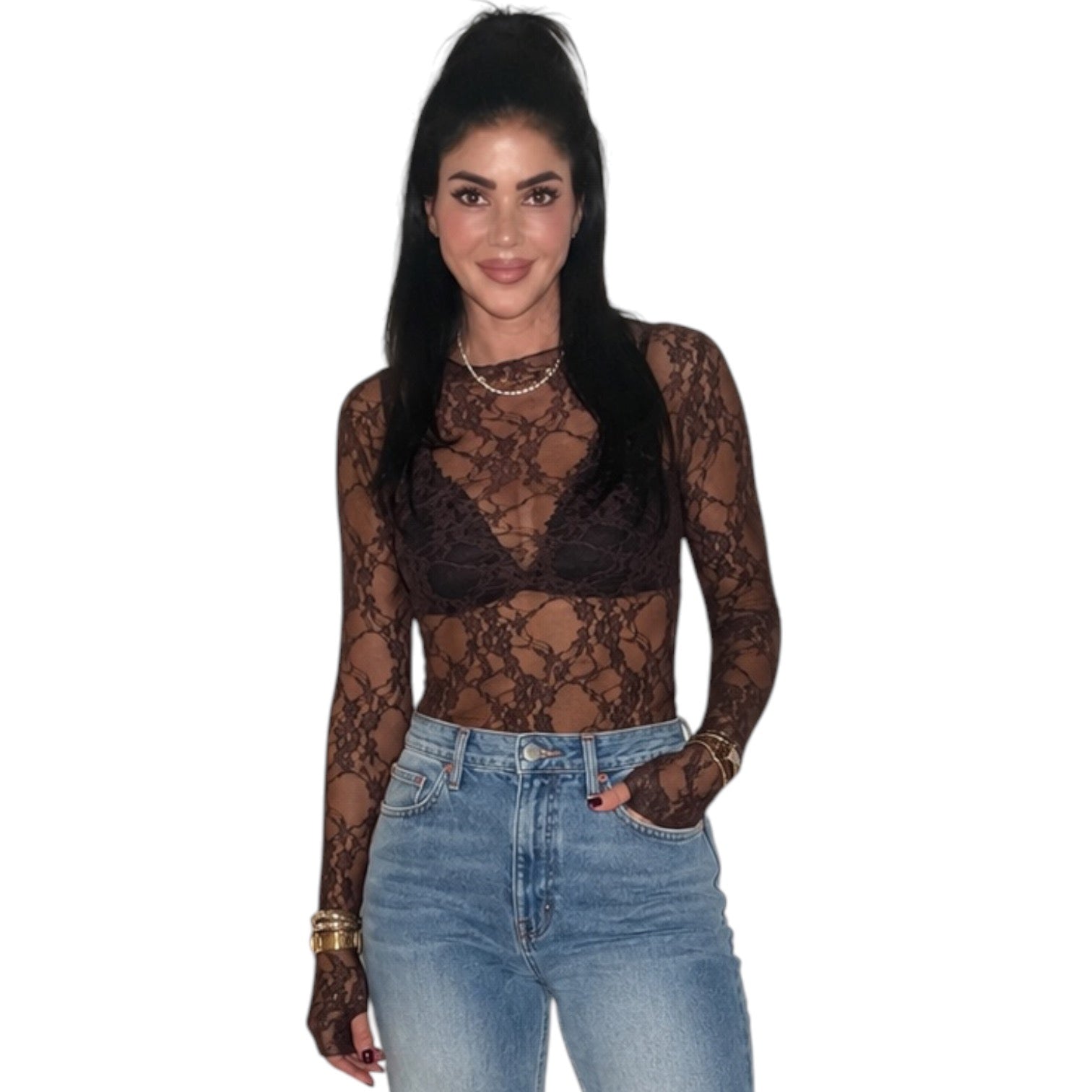 A woman modeling a sheer black lace long-sleeve top over a dark bralette, paired with light-wash blue jeans, against a plain white background.