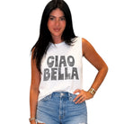 Woman wearing a white sleeveless shirt with 'CIAO BELLA' text and blue jeans on a white background