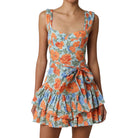 Woman wearing a floral dress with orange and blue flowers on a white background