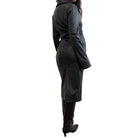 Person wearing a faux leather dress standing against a plain wall.