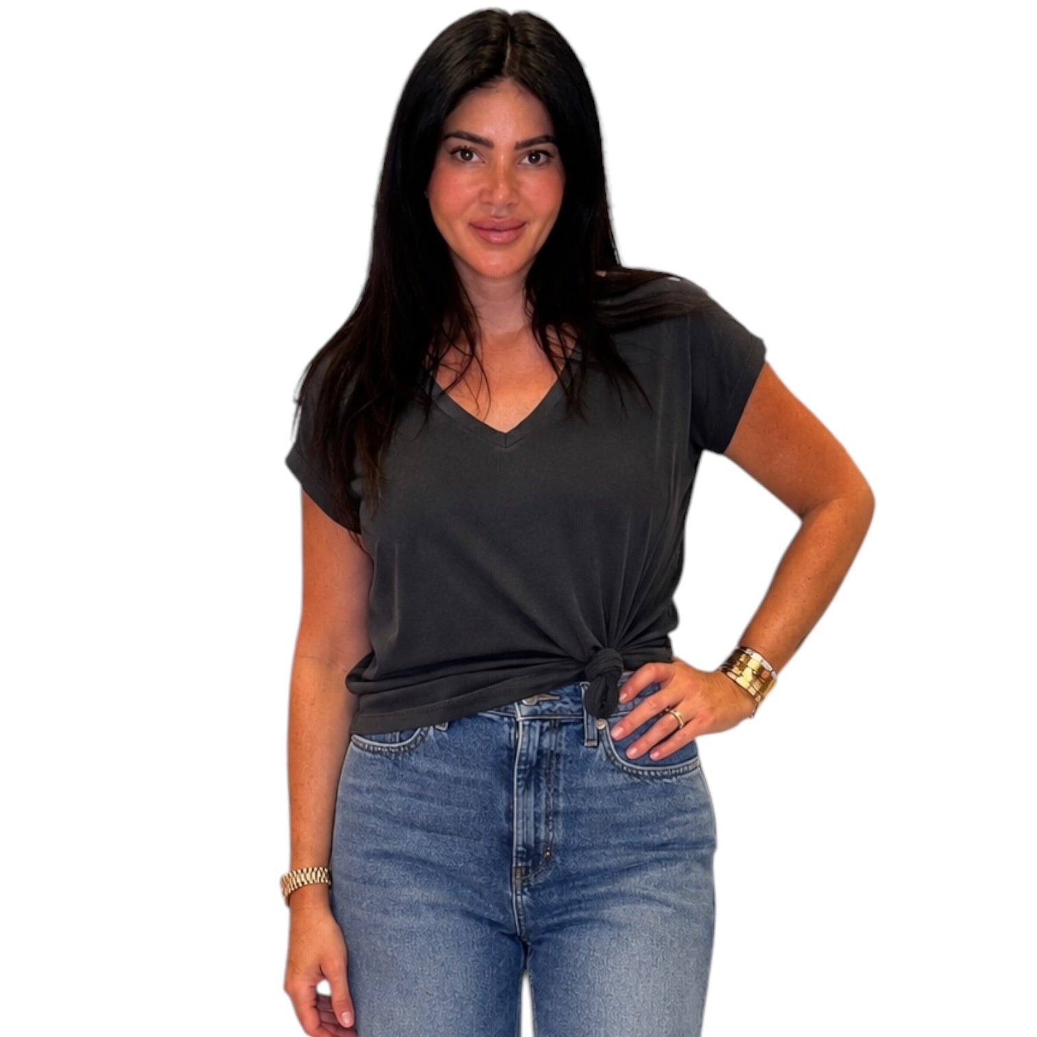 A woman modeling a vintage black v-neck t-shirt with a twisted knot at the hem, paired with blue jeans, against a plain white background.