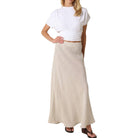 Woman wearing a white top and beige skirt on a white background