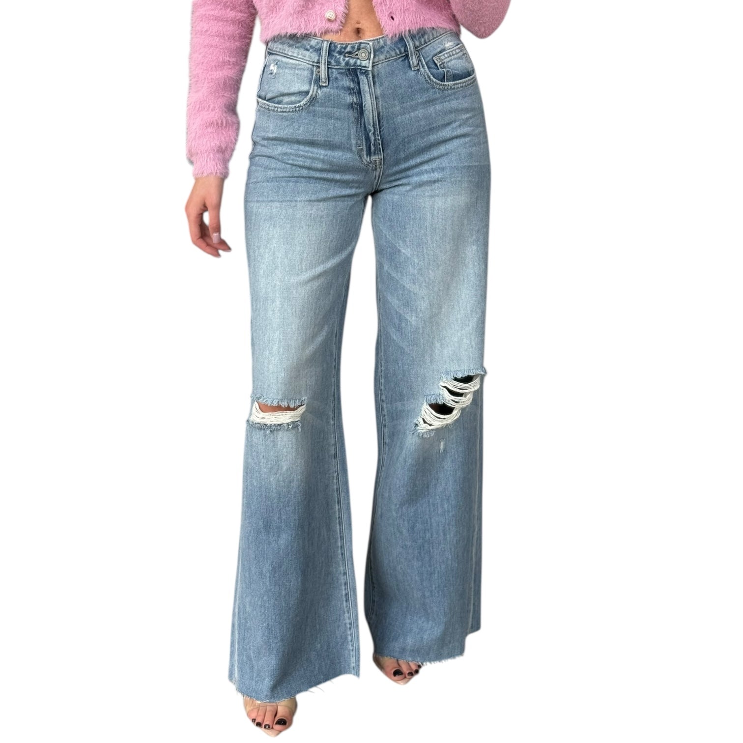 Ripped blue jeans worn by a person on a white background