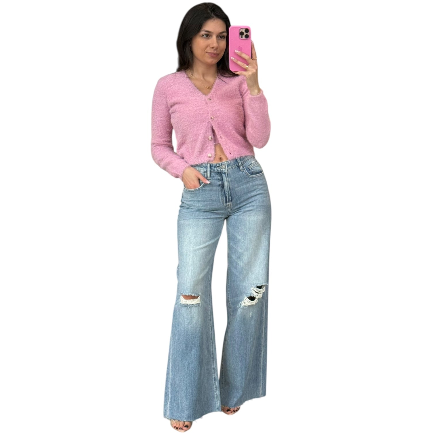 Woman wearing a pink cardigan and light blue jeans on a white background