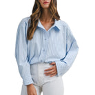 Woman wearing a light blue striped shirt and white pants on a white background
