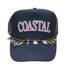 Navy blue cap with 'COASTAL' text and charm necklace on a white background