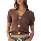 Woman wearing a brown knitted cardigan with starfish buttons on a white background