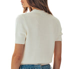 White textured short-sleeve top worn by a person on a white background