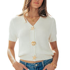 Woman wearing a white cardigan with gold buttons on a white background