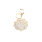 Shell-shaped keychain with gold and white details on a white background
