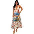 Woman wearing a colorful dress with a pattern of cherries and scenic designs on a white background