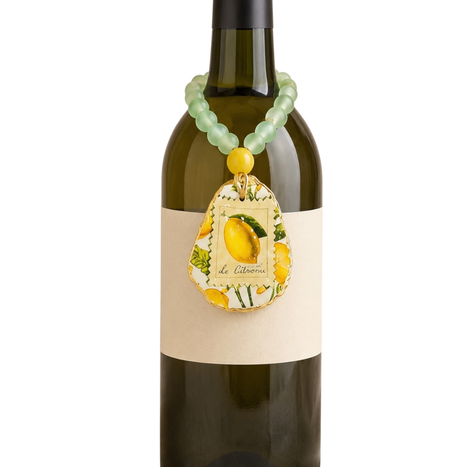 A green beaded wine bottle charm with a yellow accent bead and a decorative teardrop pendant featuring a lemon illustration and the text 'de Citron', shown hanging from a dark wine bottle against a white background.