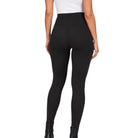Rear view of a model wearing high-waisted black leggings, a white top, and black ankle boots against a plain white background.