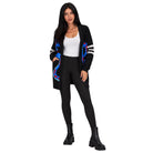 A woman modeling a black open-front cardigan with blue and red abstract swirl patterns on the front and sleeves, worn over a white tank top, black leggings, and black ankle boots against a plain white background.