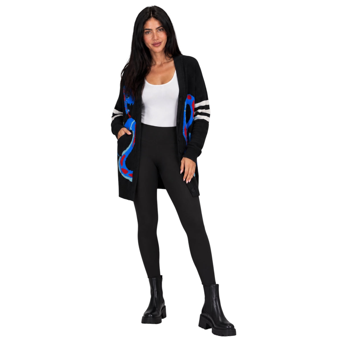 A woman modeling a black open-front cardigan with blue and red abstract swirl patterns on the front and sleeves, worn over a white tank top, black leggings, and black ankle boots against a plain white background.