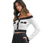 Woman wearing a black and white off-shoulder top with button details on a white background