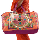 Colorful embroidered bag held by a person wearing an orange outfit on a white background