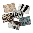 Six cardholder wallets with different animal print patterns (leopard, zebra, cowhide, and mottled blue/white) arranged on a solid white background.