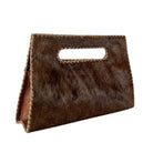 A brown cowhide handbag with a cutout handle and braided leather trim, shown on a plain white background.
