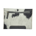 A small zippered pouch or card holder made from black-and-white cowhide with contrast tan stitching and a dark leather tab on the zipper pull, shown on a plain white background.