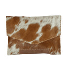 A small envelope-style clutch bag made from brown and white cowhide, shown flat against a plain white background.