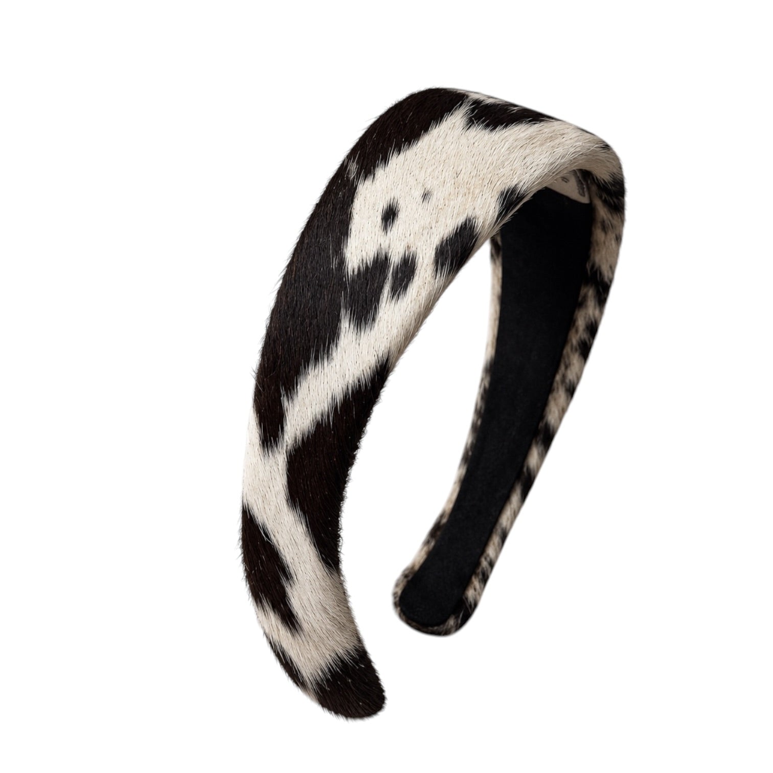 A curved black and white cow-print faux fur headband on a solid white background.