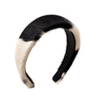 A curved faux fur headband with a black and cream color-blocked pattern, shown against a plain white background.