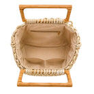 Woven handbag with wooden handle and stand on a white background