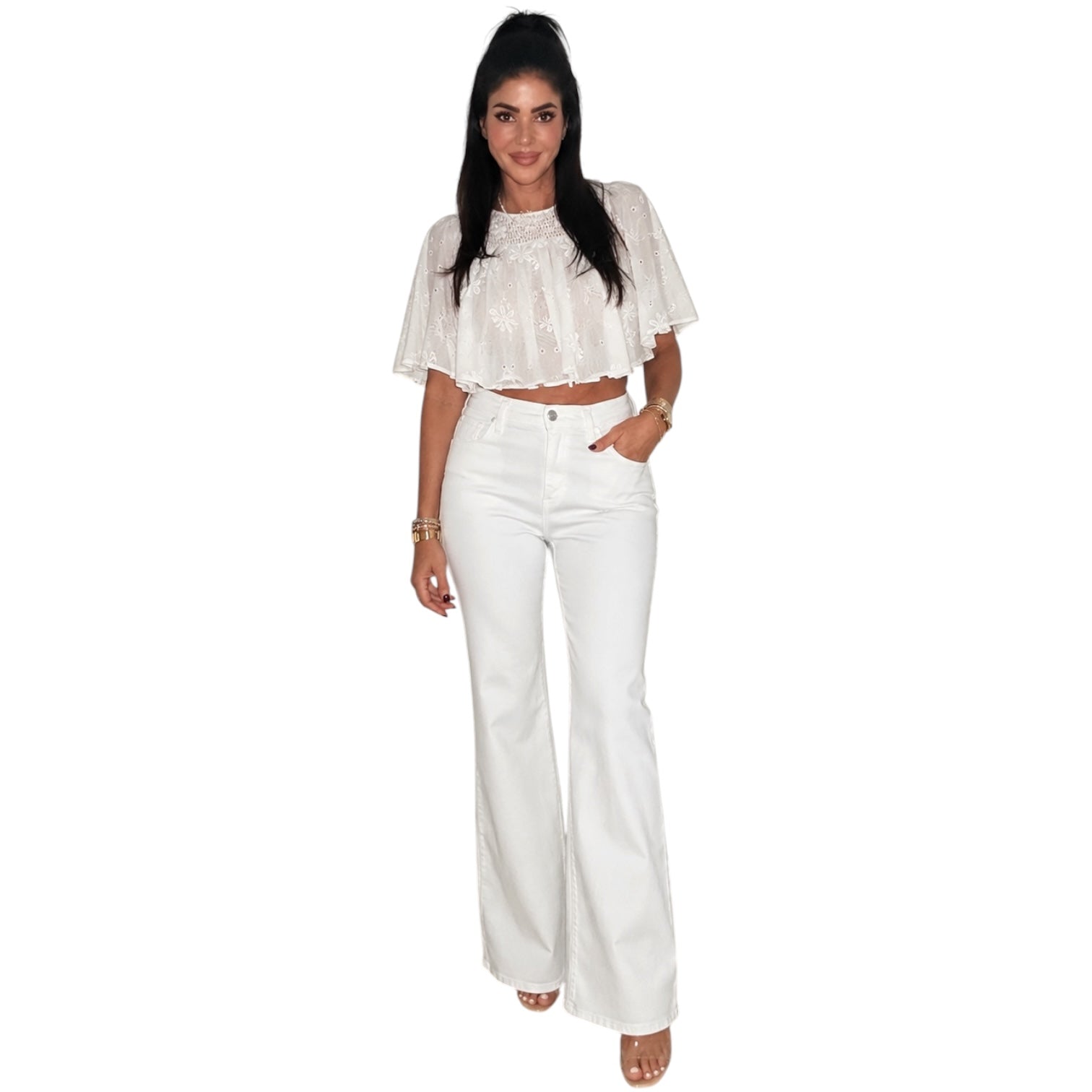 a woman wearing a cream embroidered top with white jeans